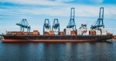 Large cargo ship with colorful metal containers floating on rippling water of ocean under cloudy blue sky in daylight