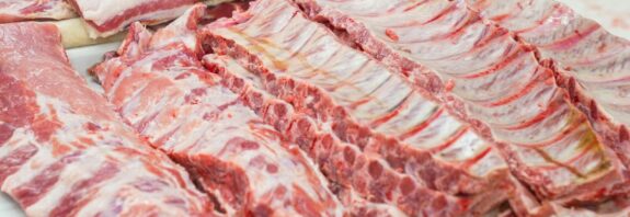 Close-up of fresh raw pork ribs neatly arranged on a cutting board, showcasing marbling.