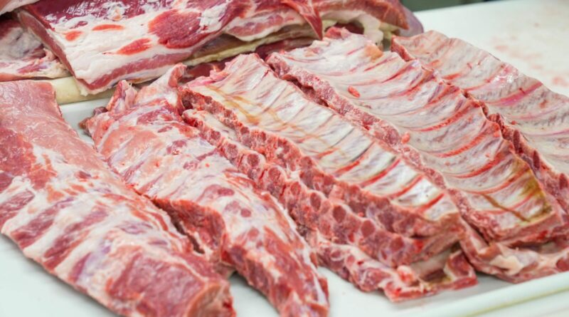 Close-up of fresh raw pork ribs neatly arranged on a cutting board, showcasing marbling.